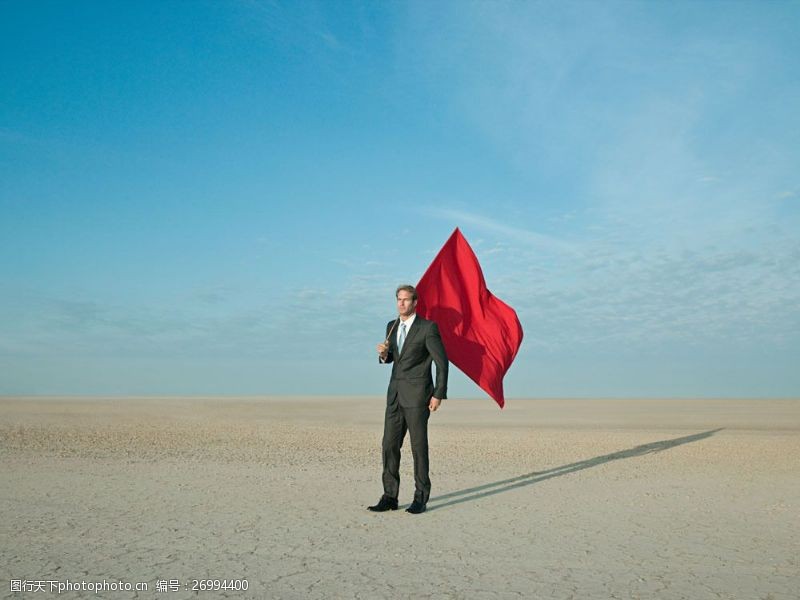 气候扛着红旗站在沙漠中的商业男人图片
