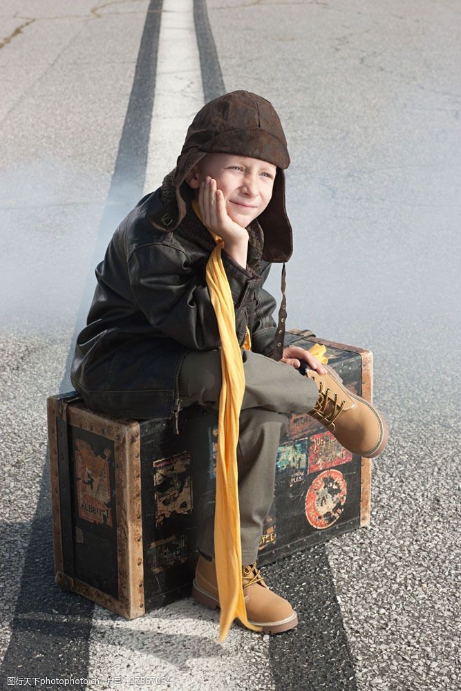 坐驾坐着行李箱上发呆的小男孩图片