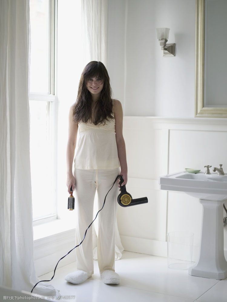 白色的洗衣机拿着吹风机和梳子的女人图片