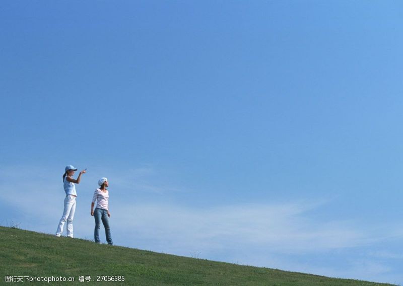 假日休闲女性站在草地上看着远方的两美女图片