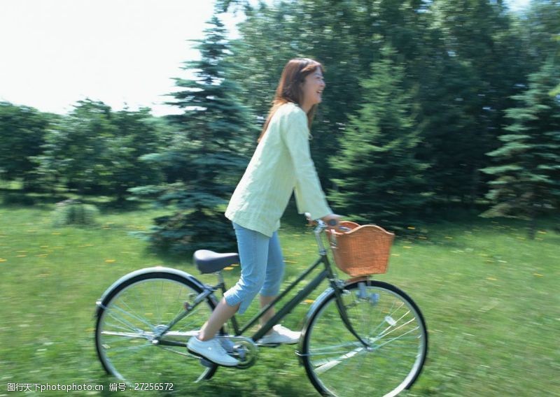假日休闲女性草地上开心骑自行车的美女图片
