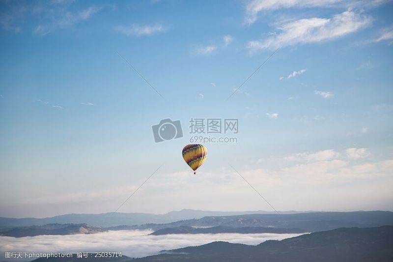 黄色和绿色的热气球在空中漂浮在蓝色中期和白天晴云的天空