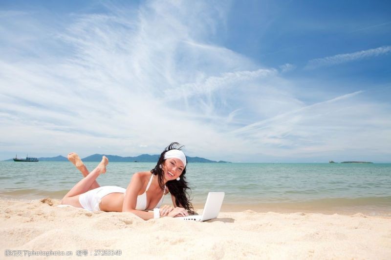 海滩上的美女趴在沙滩上上网的时尚美女图片图片