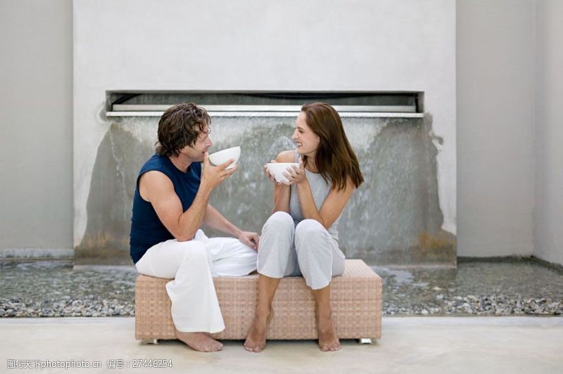 手捧水水池边坐着喝水的外国情侣图片