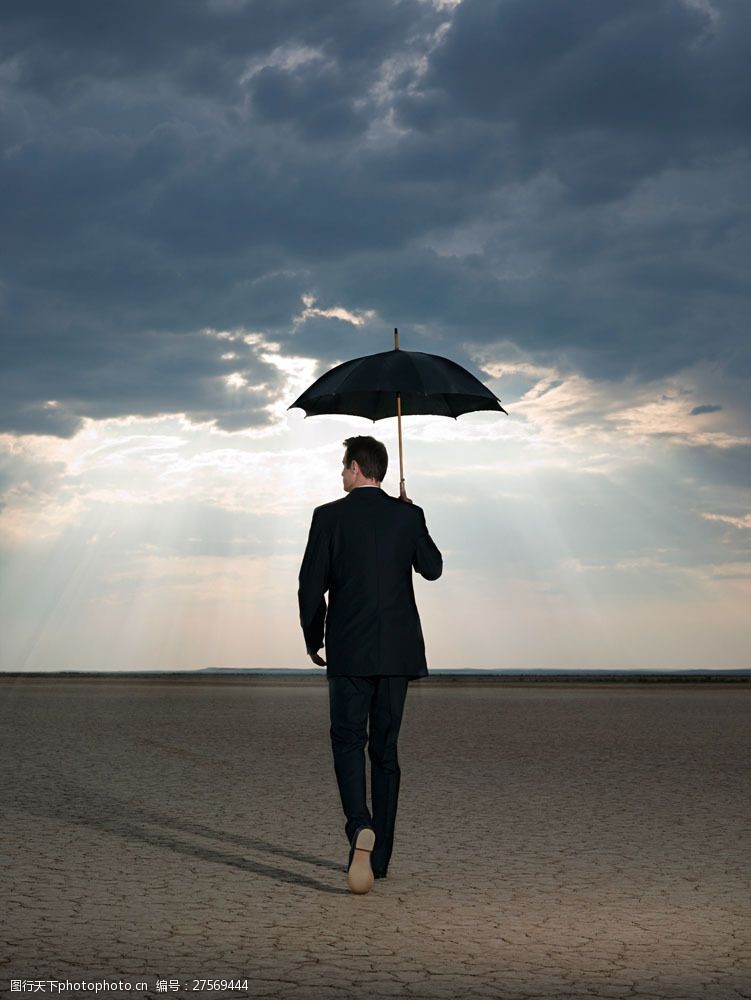 拿的姿势打着雨伞走在旱地里的外国男人图片