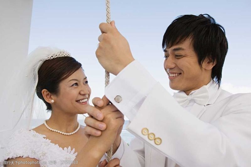 握着手面带笑容穿着婚纱礼服手握绳子的男女图片图片