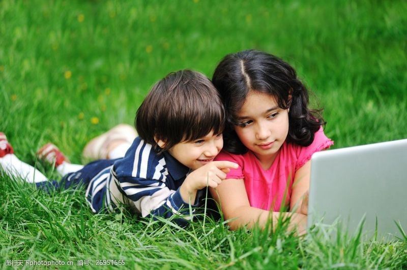 laptop趴草地上玩电脑的儿童图片