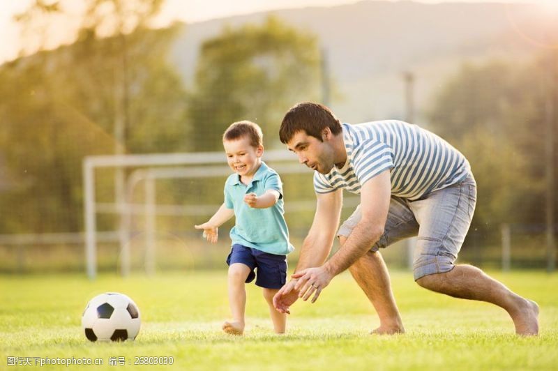 踢球草地上踢足球的父子图片